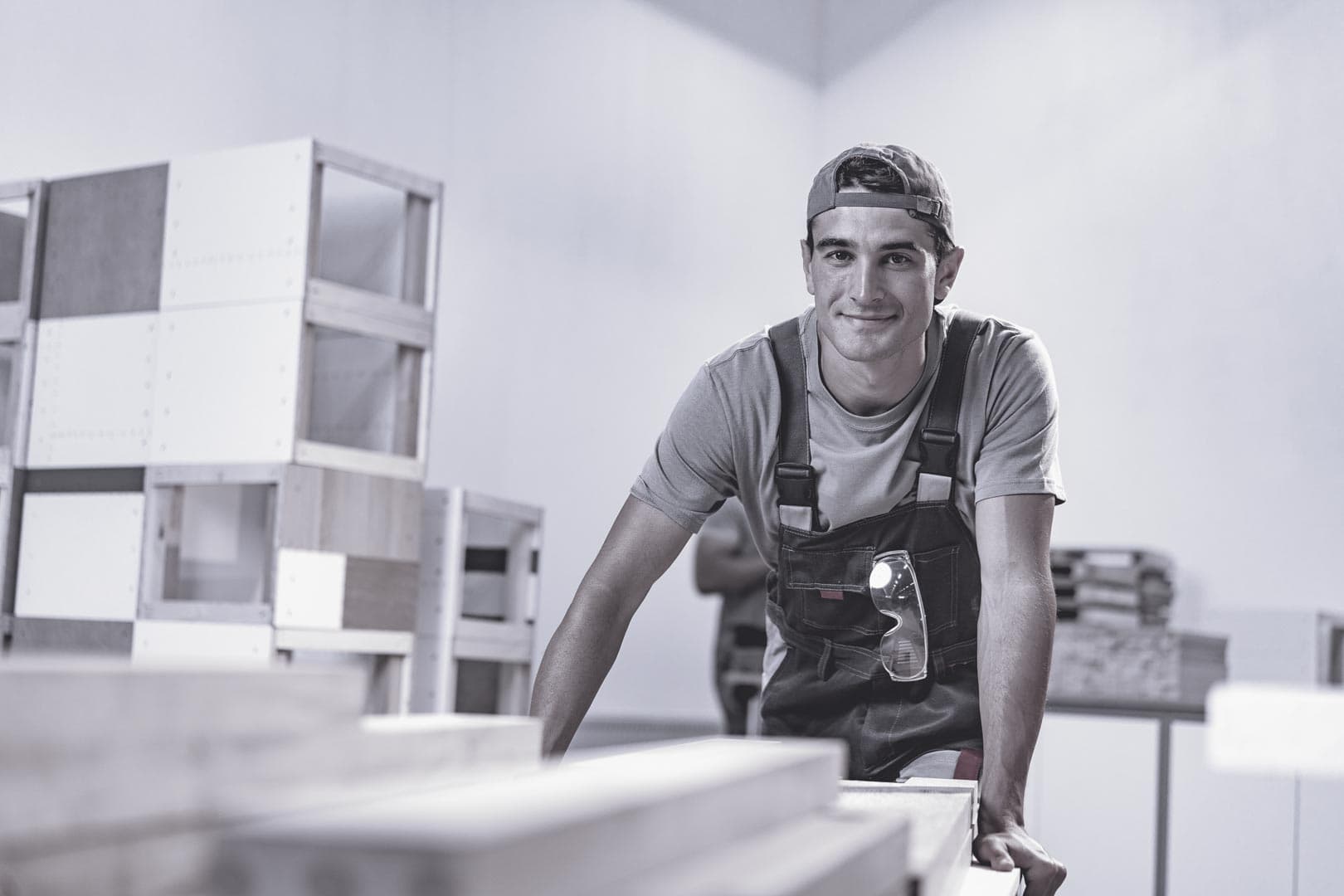 Artisan menuisier dans son atelier, au milieu de ses réalisations en bois.