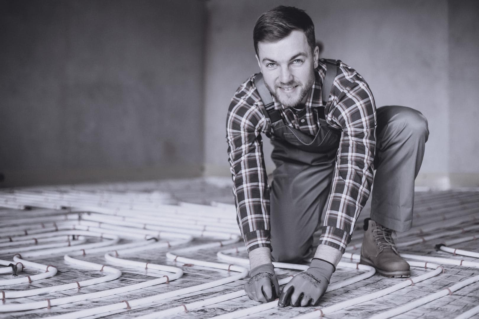 Artisan chauffagiste réalisant la pose d'un plancher chauffant.